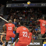 Volleyball players from Canada and Cuba competing at the net during a match