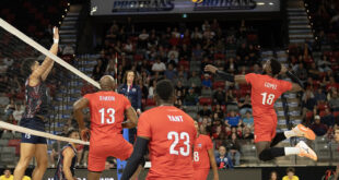 Volleyball players from Canada and Cuba competing at the net during a match