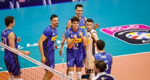 Volleyball players from Finland and Greece competing at the net during a EuroVolley match.
